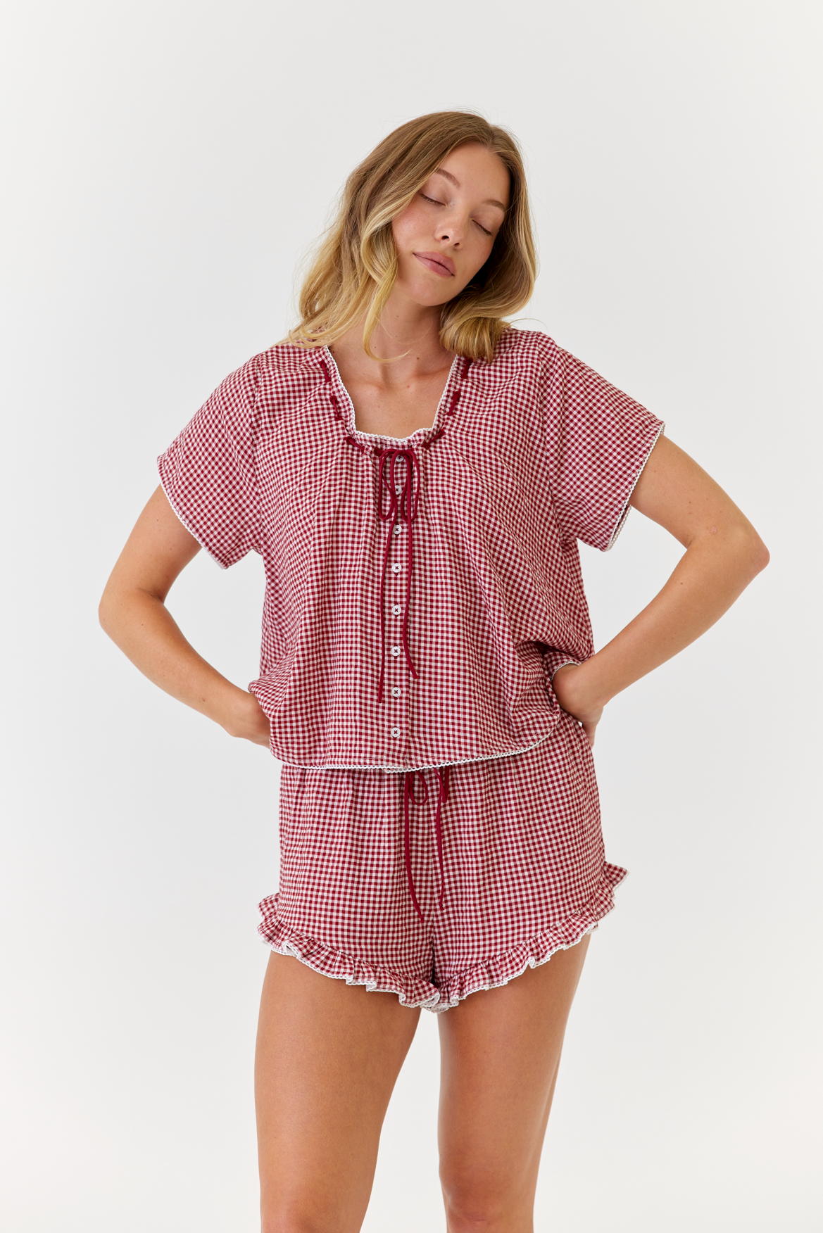 Woman wearing a red and white checkered pajama set on a white background