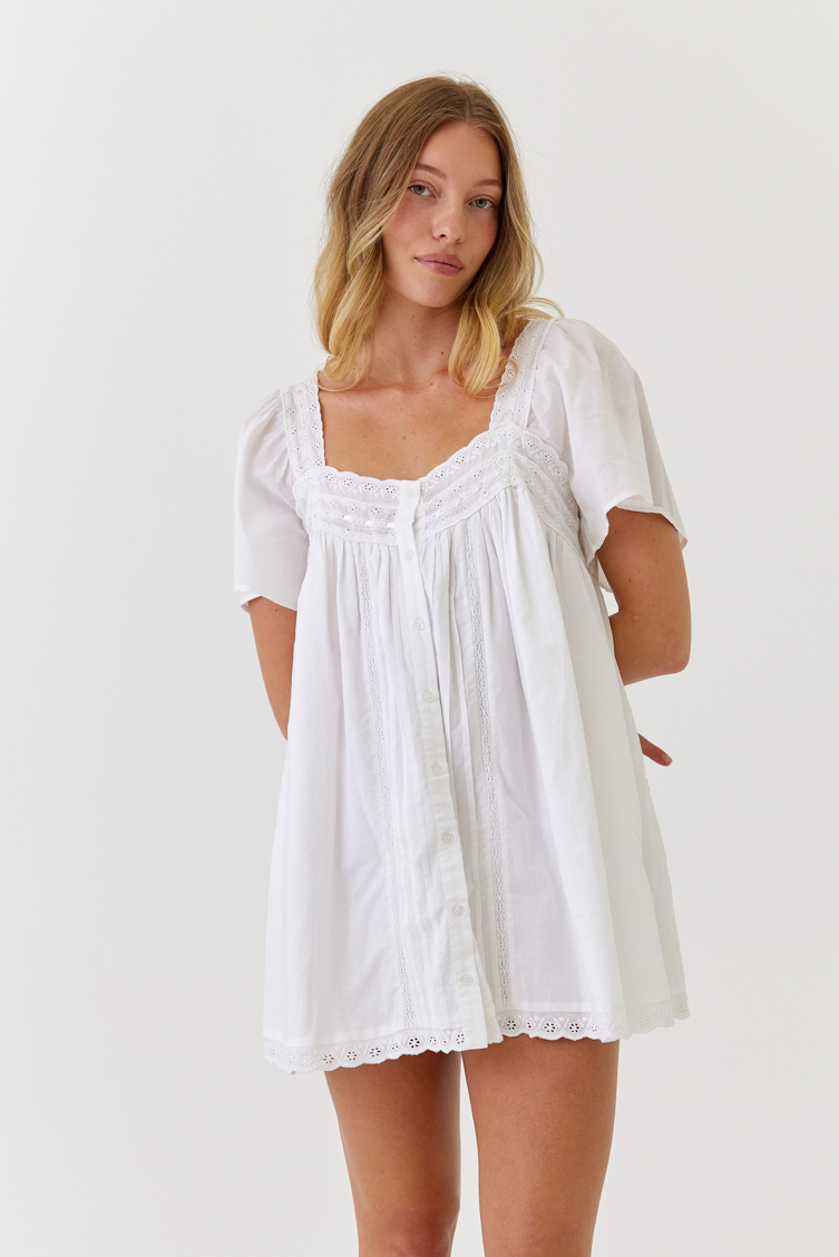 White cotton dress with vintage lace detail worn by a bride while getting ready