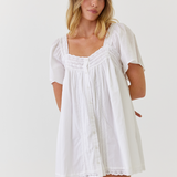 White cotton dress with vintage lace detail worn by a bride while getting ready