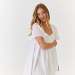 Model wearing lightweight white mini dress styled for summer