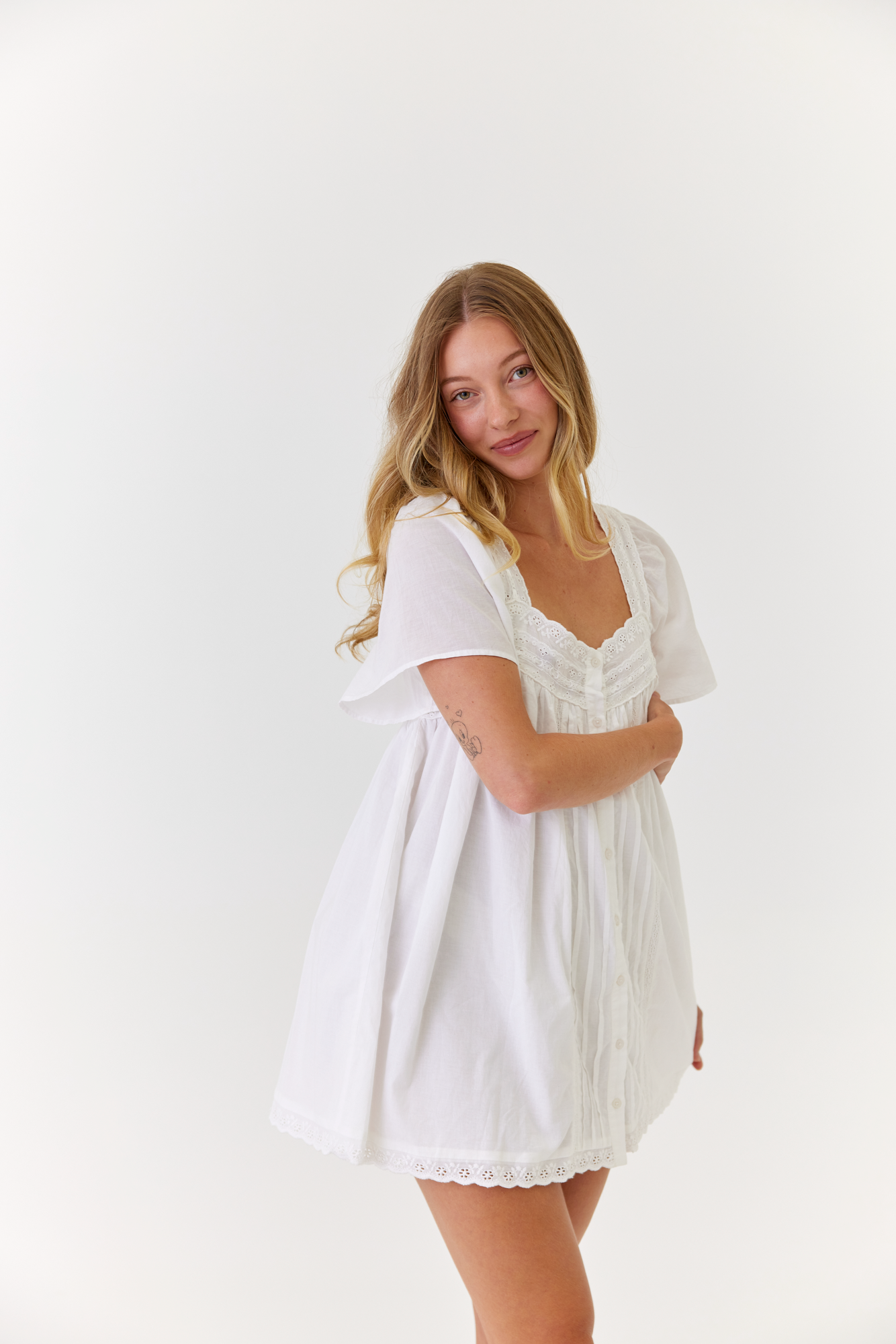 Model wearing lightweight white mini dress styled for summer